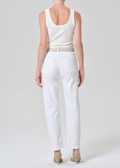 Person wearing a white tank top and white jeans on a plain background