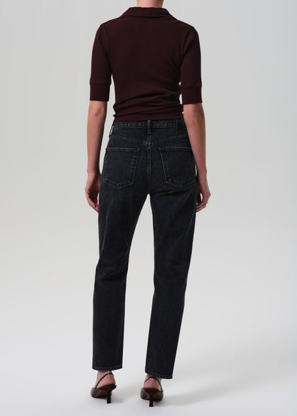 Person wearing a brown polo shirt and black jeans on a white background