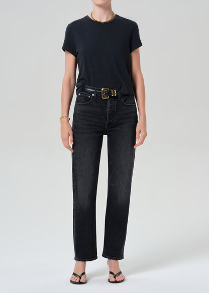 Person wearing a black t-shirt and black jeans on a grey background