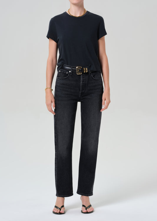 Person wearing a black t-shirt and black jeans on a grey background