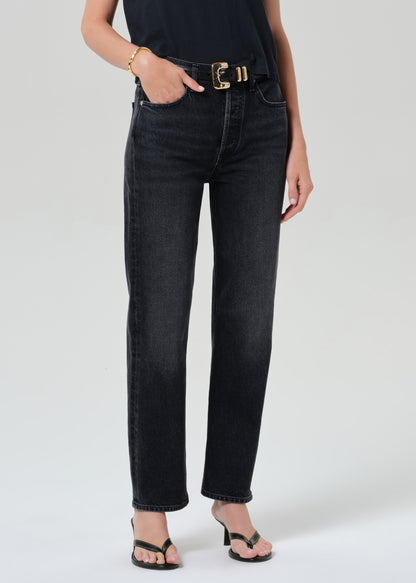 Person wearing a black t-shirt and black jeans on a grey background