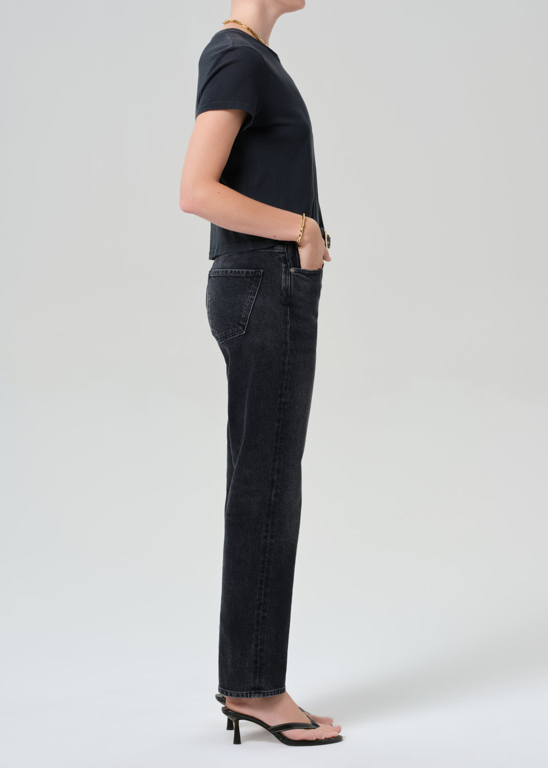 Person wearing a black t-shirt and black jeans on a grey background