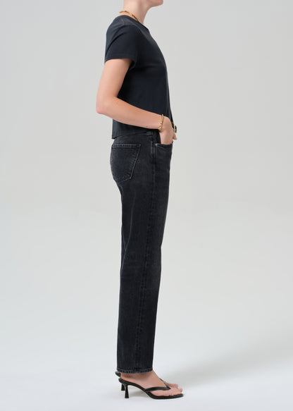 Person wearing a black t-shirt and black jeans on a grey background
