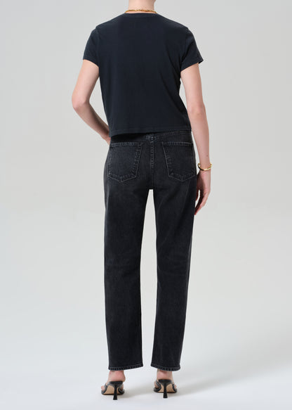 Person wearing a black t-shirt and black jeans on a grey background