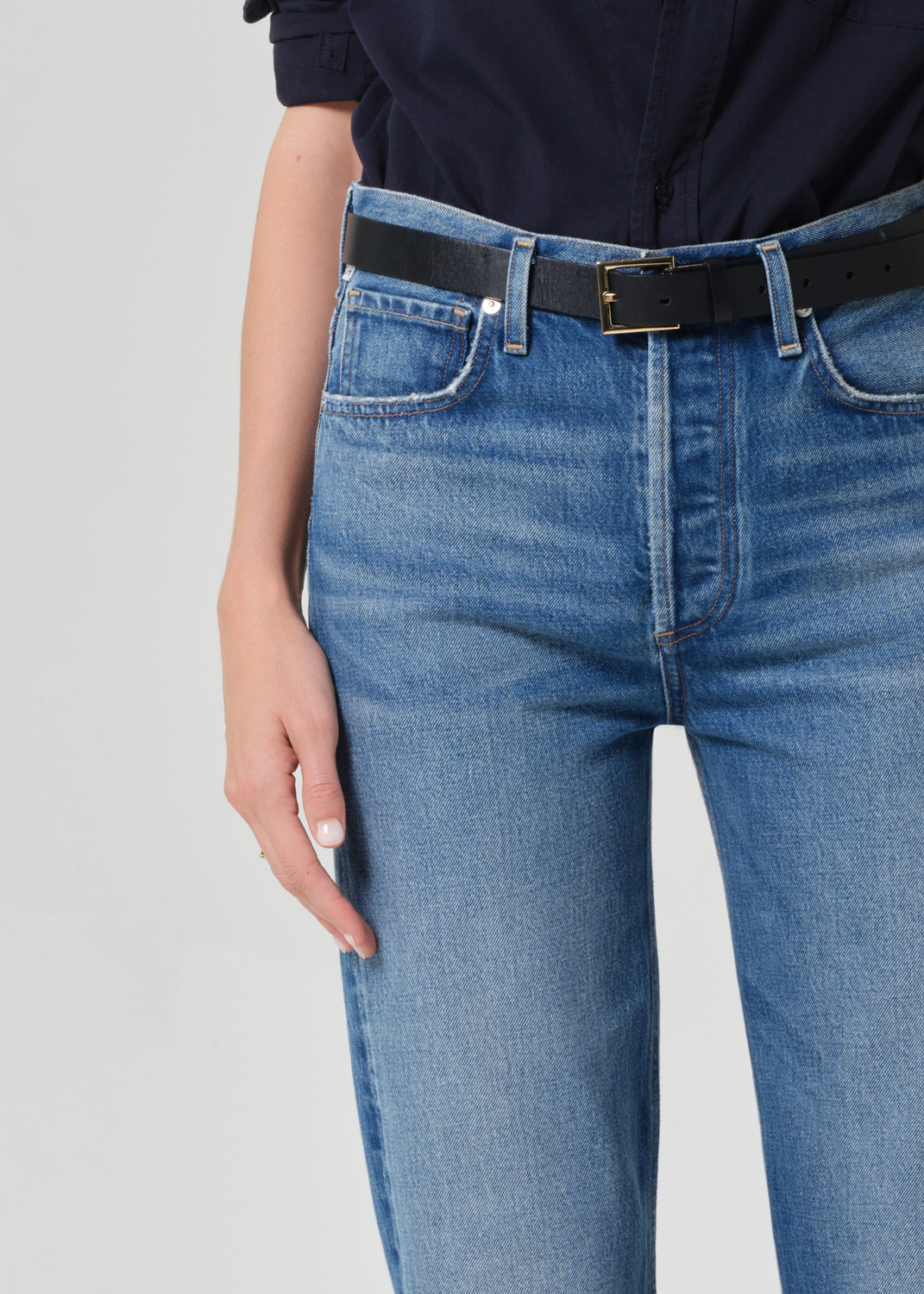 Blue jeans with a black belt on a gray background