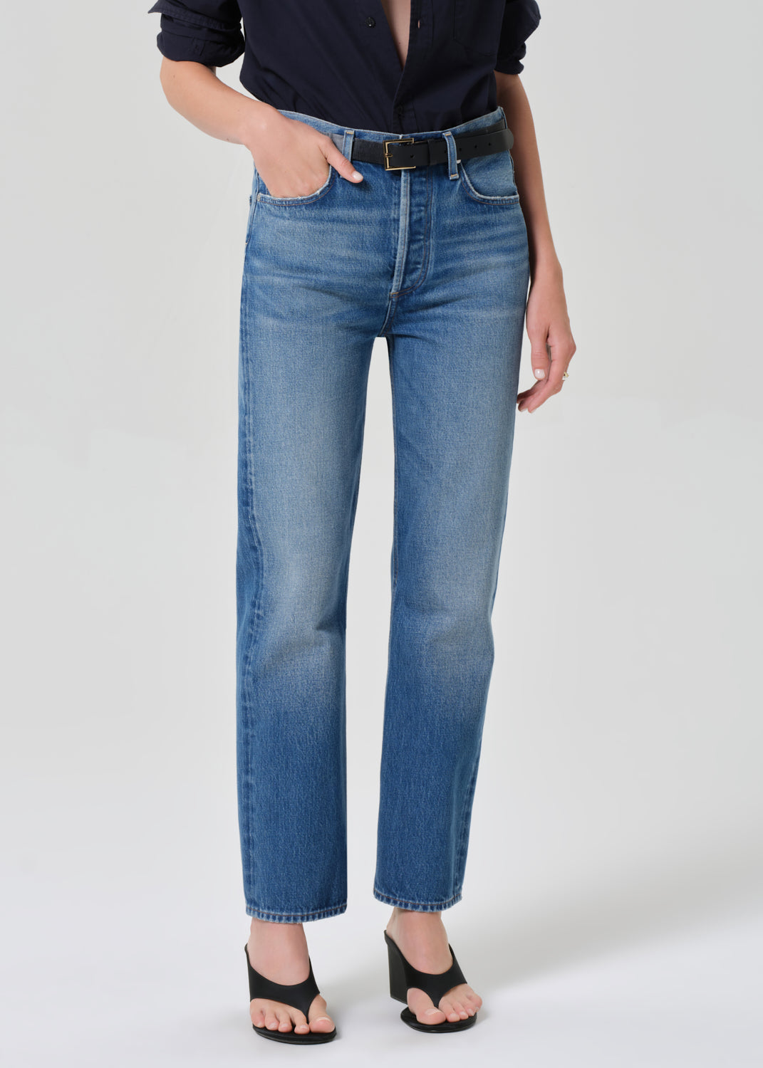 Person wearing blue jeans on a grey background