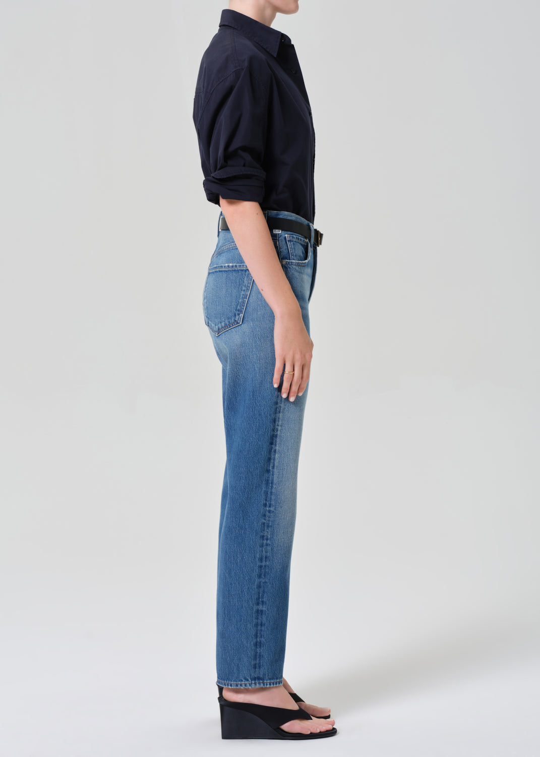 Person wearing blue jeans and a navy shirt on a grey background