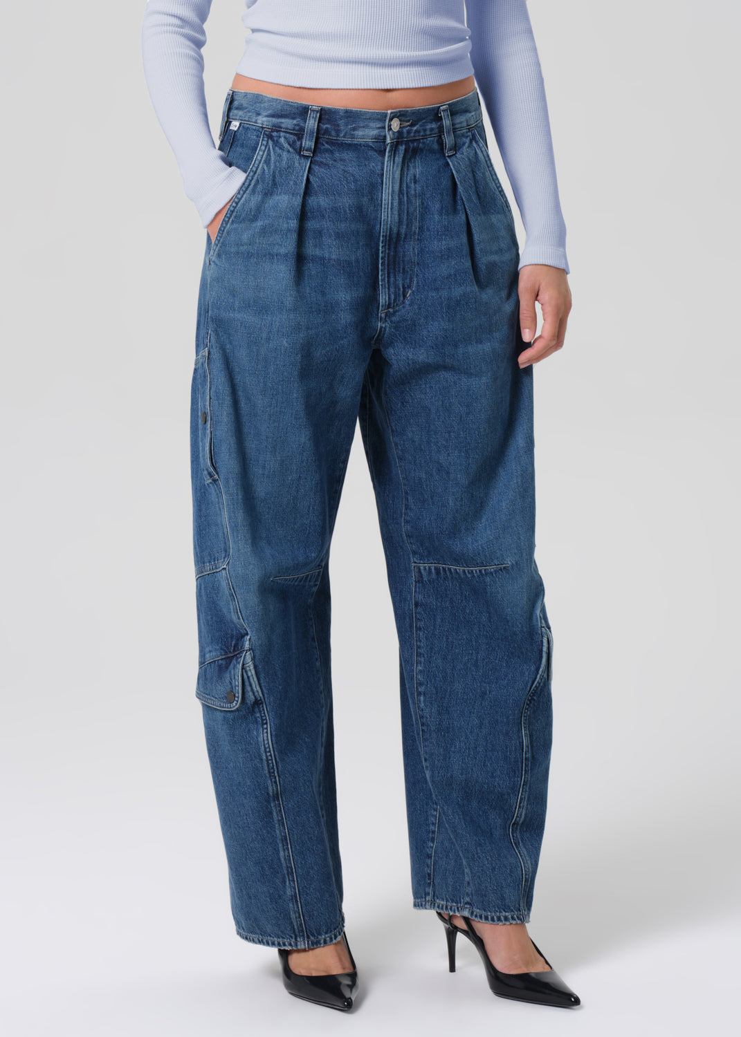 Person wearing blue jeans and a light blue top on a grey background