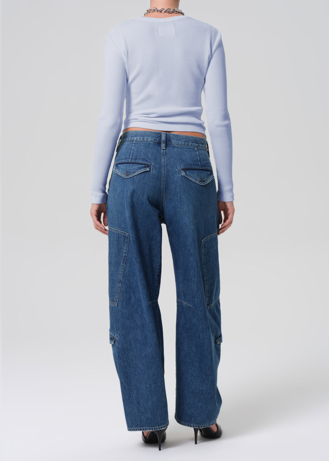 Person wearing blue jeans and a light blue long-sleeve top on a white background