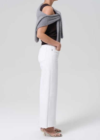 Person wearing a brown sleeveless top, white pants on a light gray background