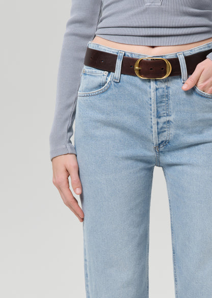 Person wearing a gray long-sleeve top and light blue jeans on a grey background