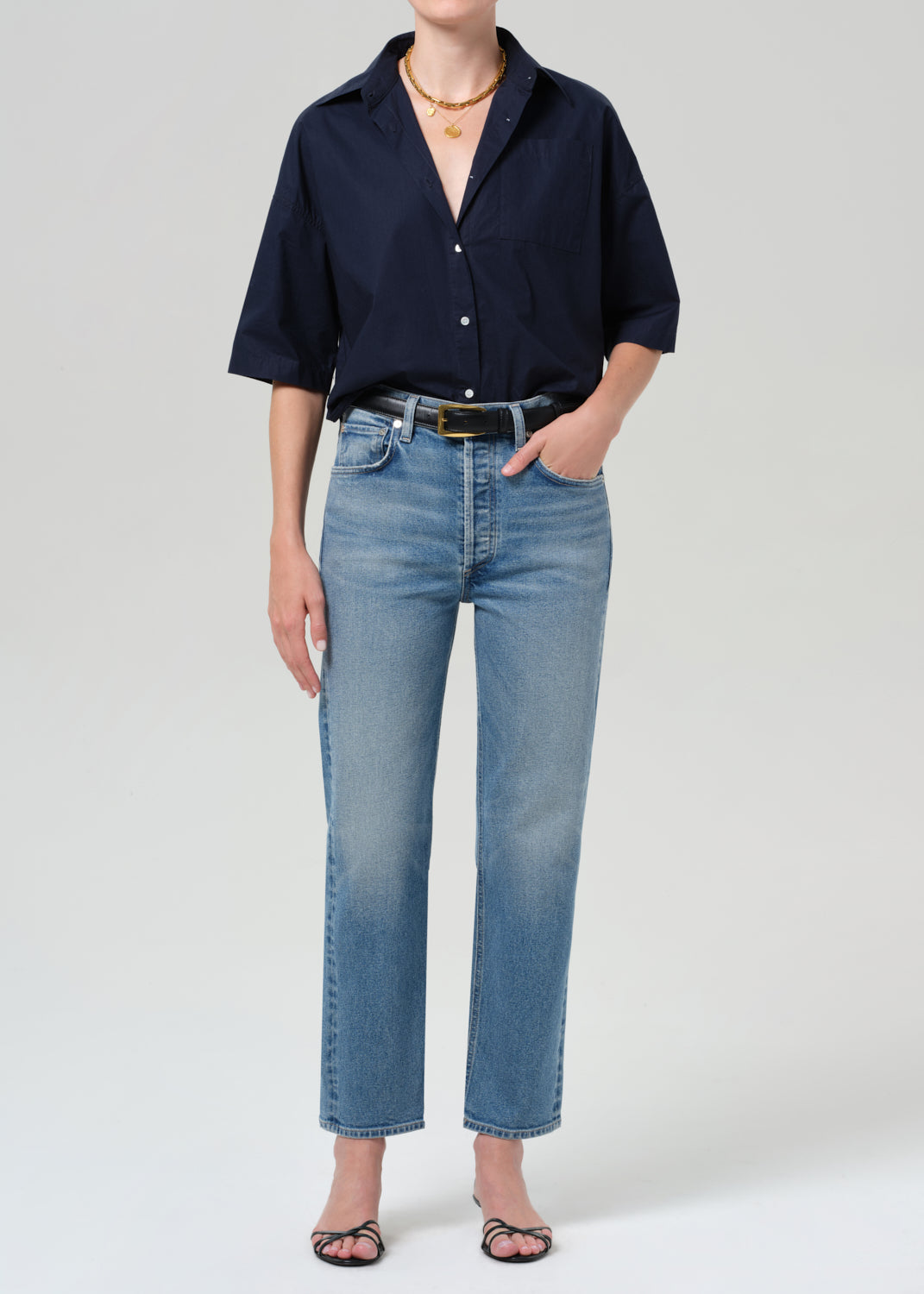 Person wearing a navy shirt and light blue jeans on a plain background