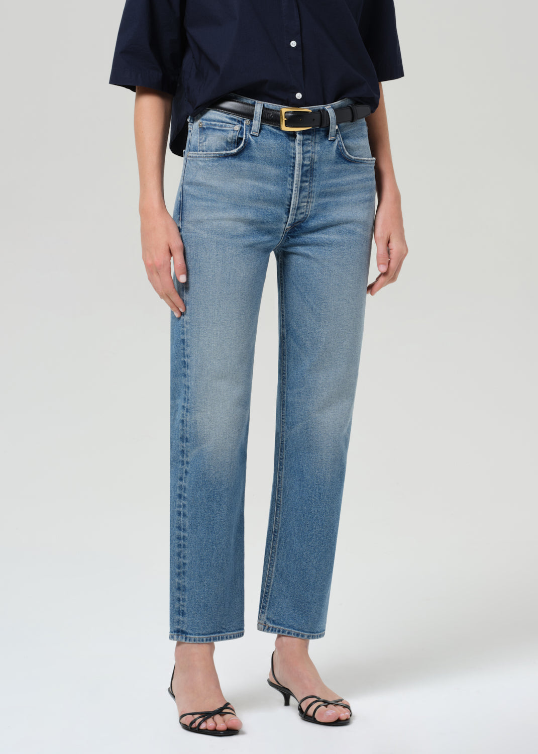 Person wearing blue jeans and a navy shirt on a grey background