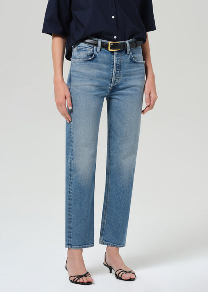 Person wearing blue jeans and a navy shirt on a grey background