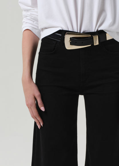 Person wearing a white shirt and black jeans on a plain background