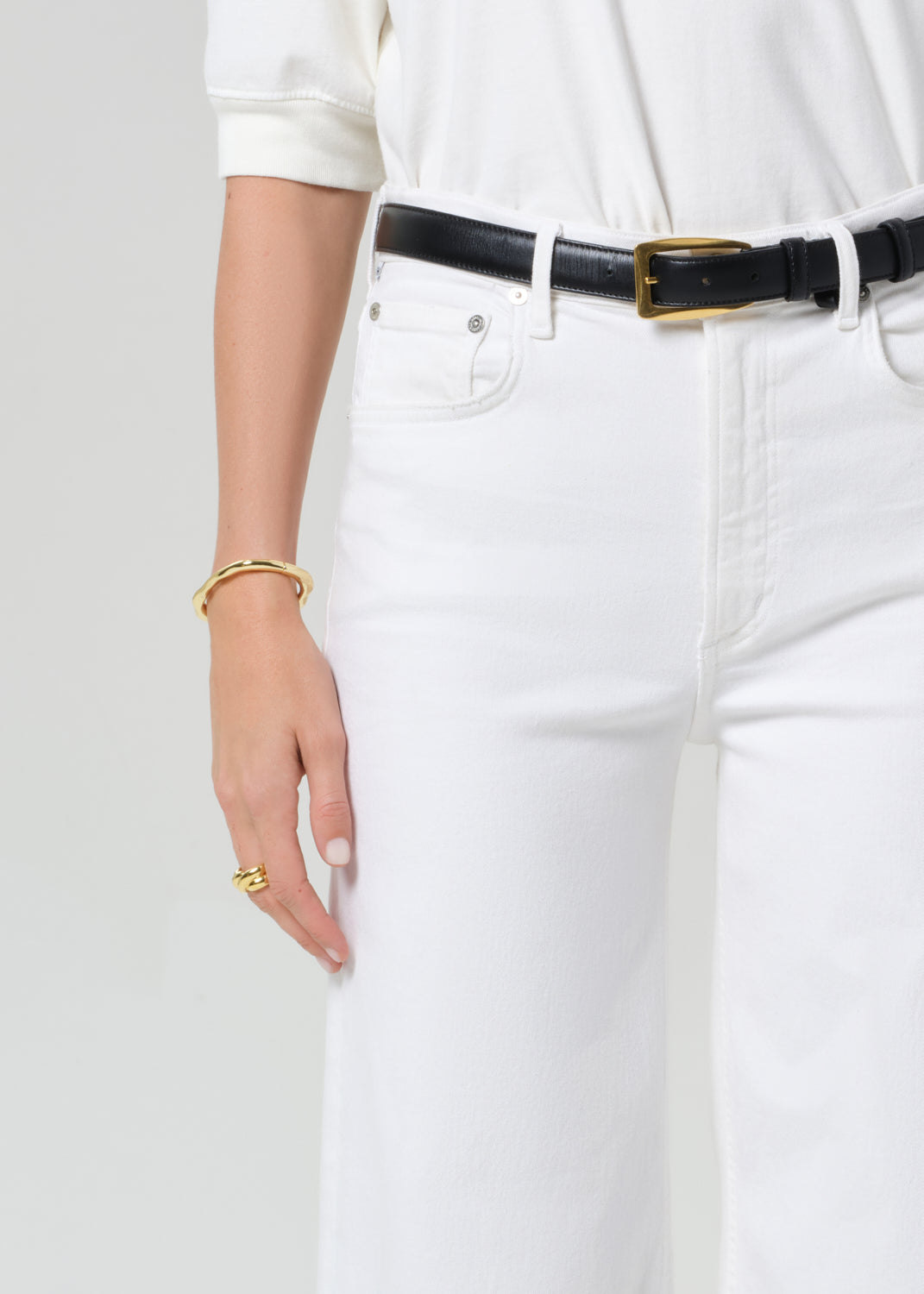 White jeans with a black belt on a plain background