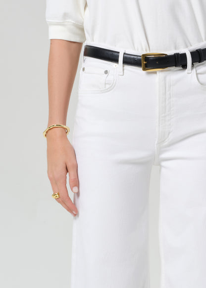 White jeans with a black belt on a plain background