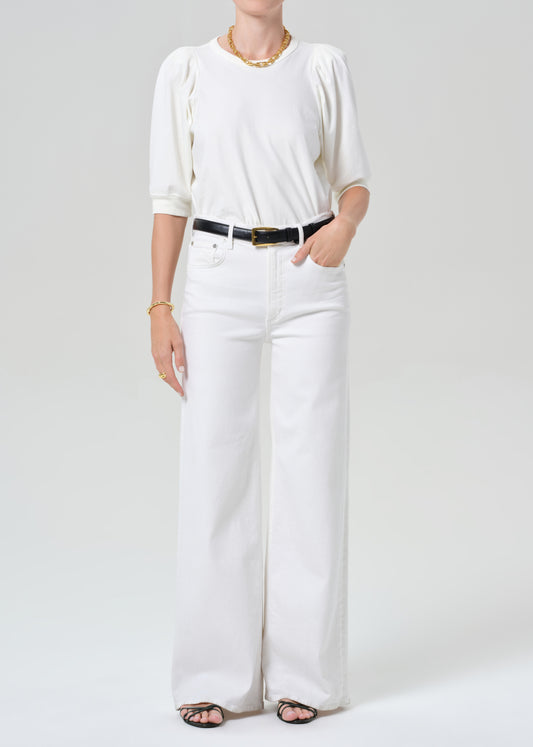 Person wearing a white outfit with a black belt on a plain background