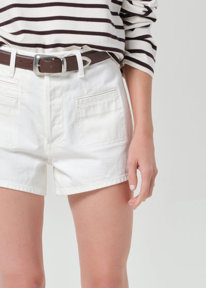 Person wearing a brown and white striped sweater with white shorts on a plain background