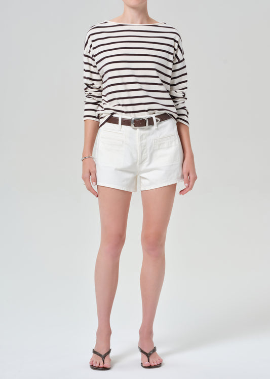 Person wearing a brown and white striped sweater with white shorts on a plain background