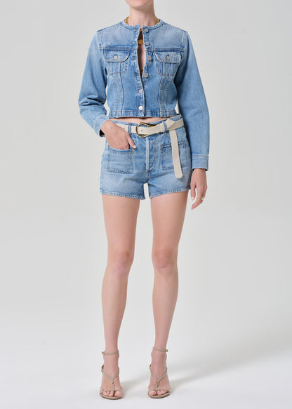 Person wearing a denim jacket and shorts on a grey background