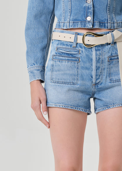 Person wearing a denim jacket and shorts on a grey background