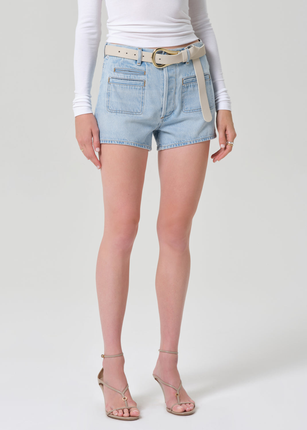 Person wearing light blue denim shorts with a white background
