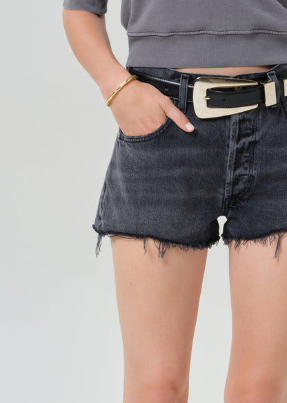 Person wearing a gray sweatshirt and black denim shorts on a grey background