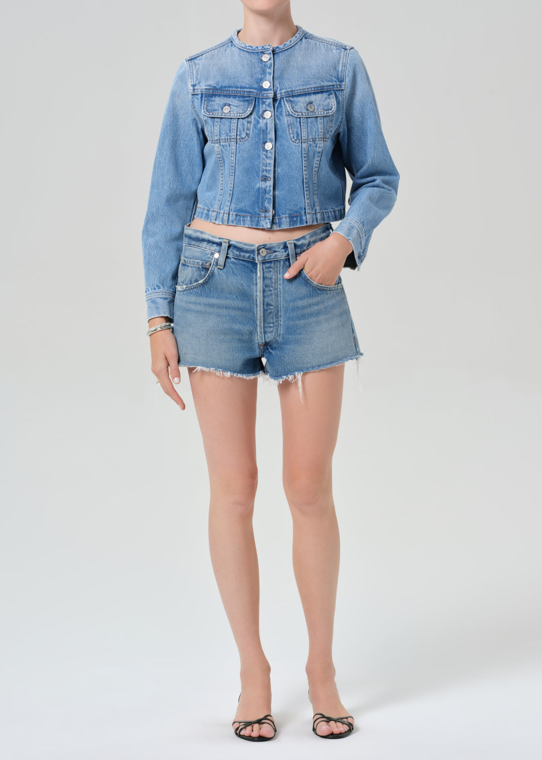 Person wearing a denim jacket and shorts on a white background