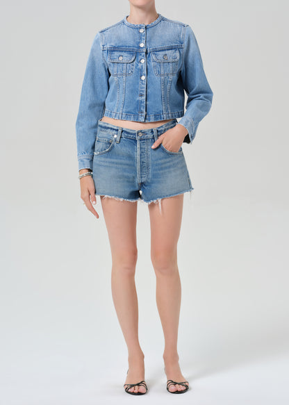 Person wearing a denim jacket and shorts on a white background