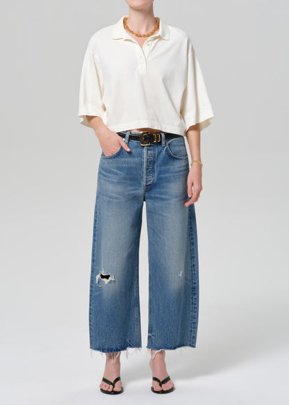 Person wearing a white shirt and blue jeans on a plain background