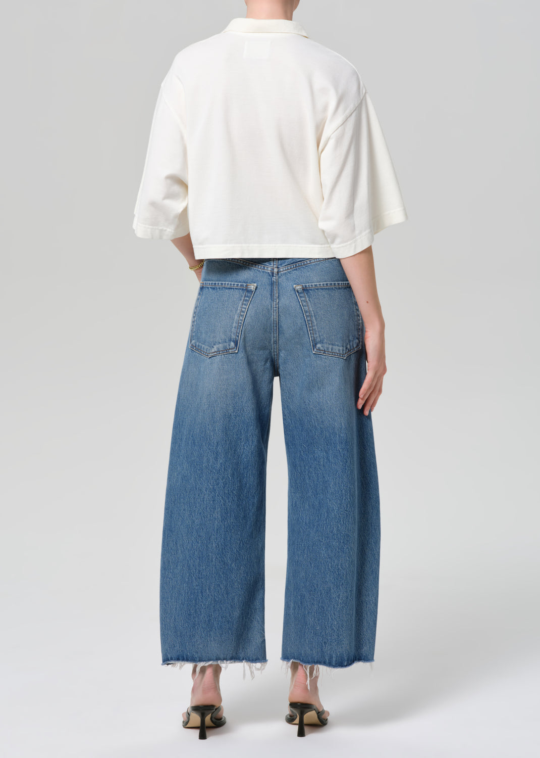 Person wearing a white top and blue jeans on a plain background