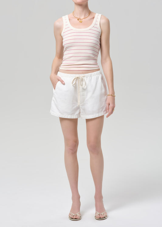 Person wearing a striped tank top and white shorts on a plain background