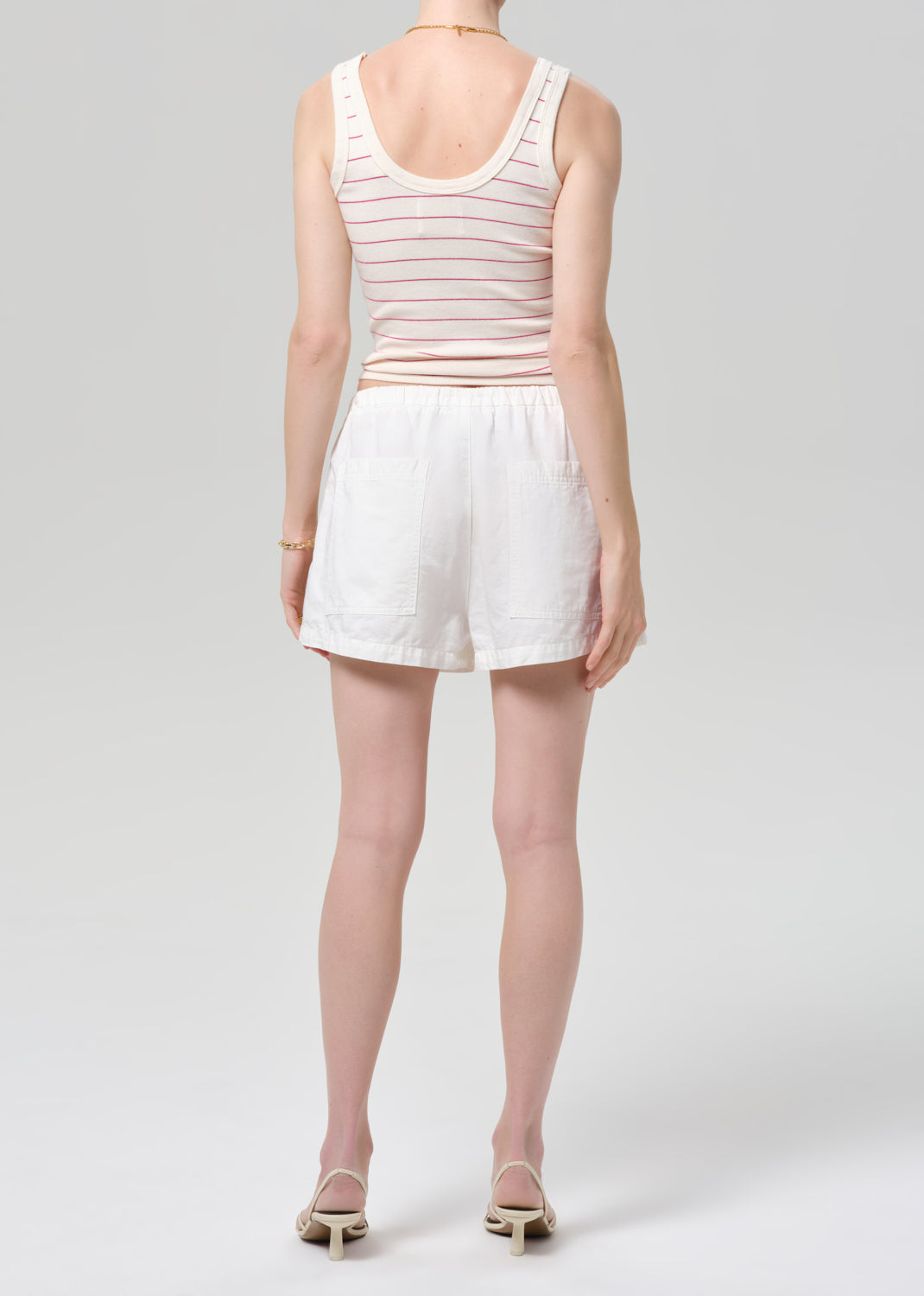 Person wearing a striped tank top and white shorts on a plain background