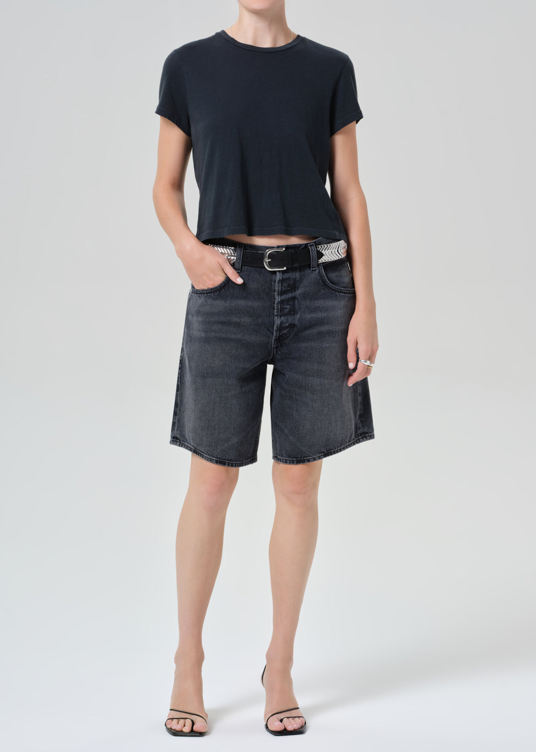 Person wearing a black t-shirt and denim shorts on a plain background