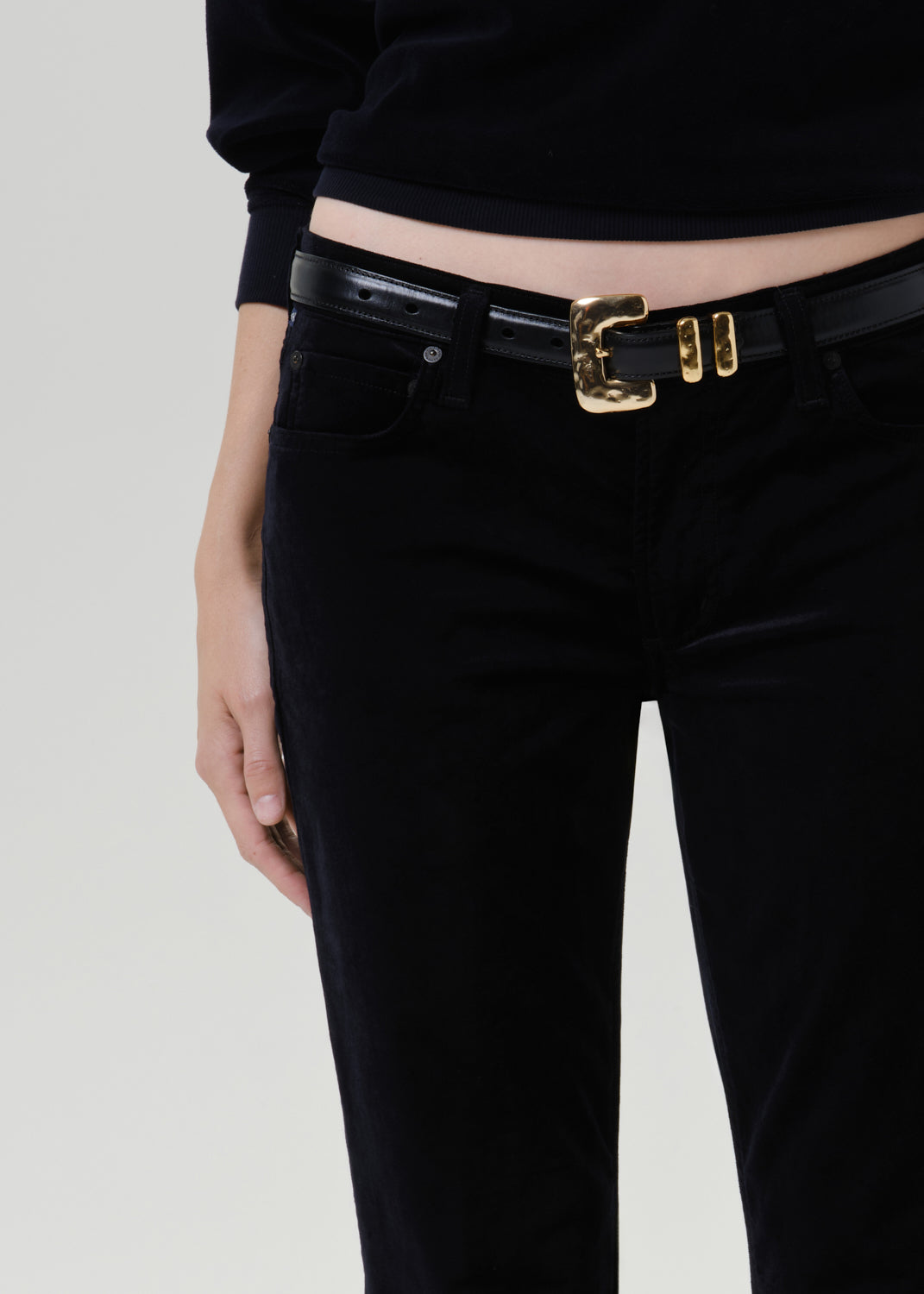 Close up shot of person wearing black belt with black pants on a grey background