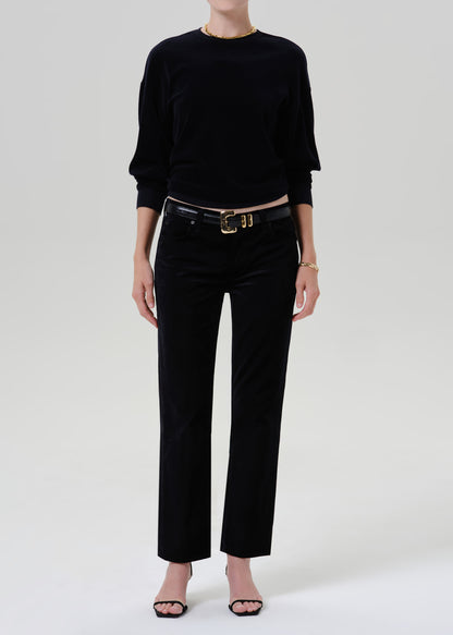 Person wearing black sweater with black pants and belt on a grey background