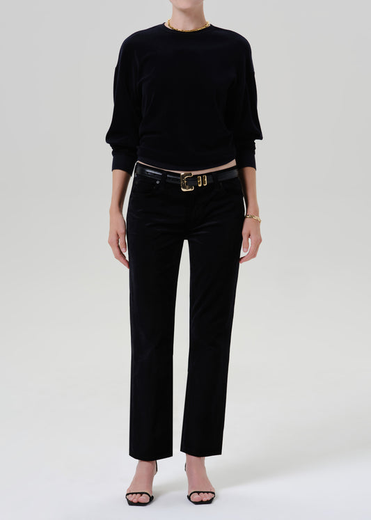 Person wearing black sweater with black pants and belt on a grey background