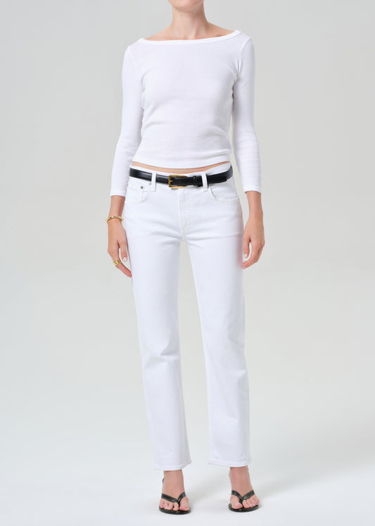 Person wearing a white long-sleeve top and white pants on a plain background