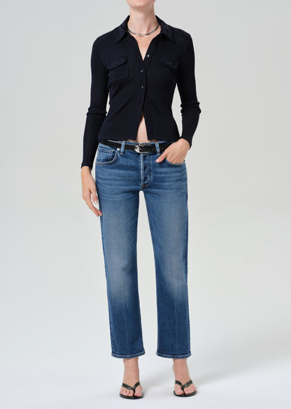 Person wearing a navy shirt and blue jeans on a grey background