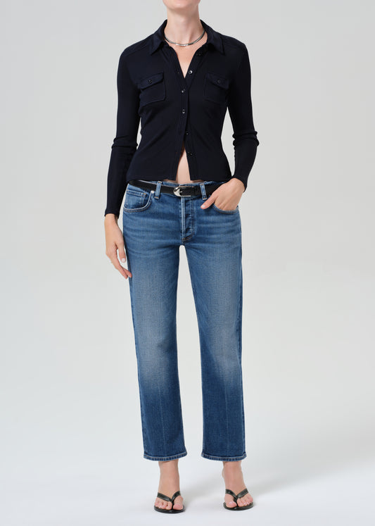 Person wearing a navy shirt and blue jeans on a grey background