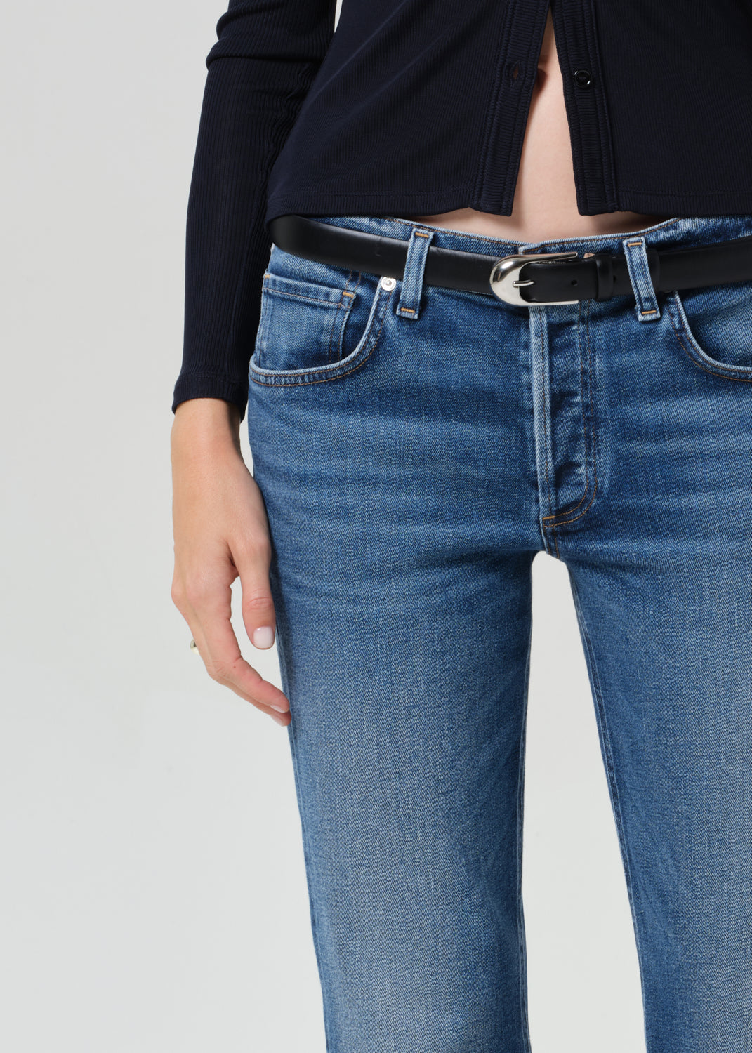 Person wearing a navy shirt and blue jeans on a grey background