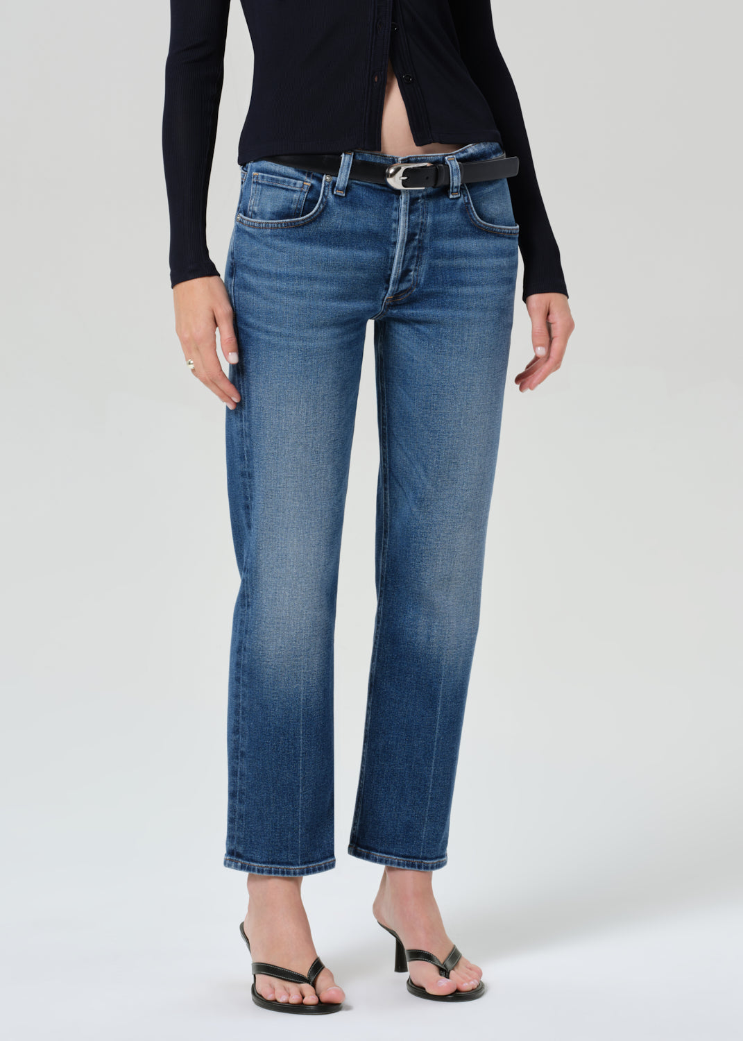 Person wearing a navy shirt and blue jeans on a grey background