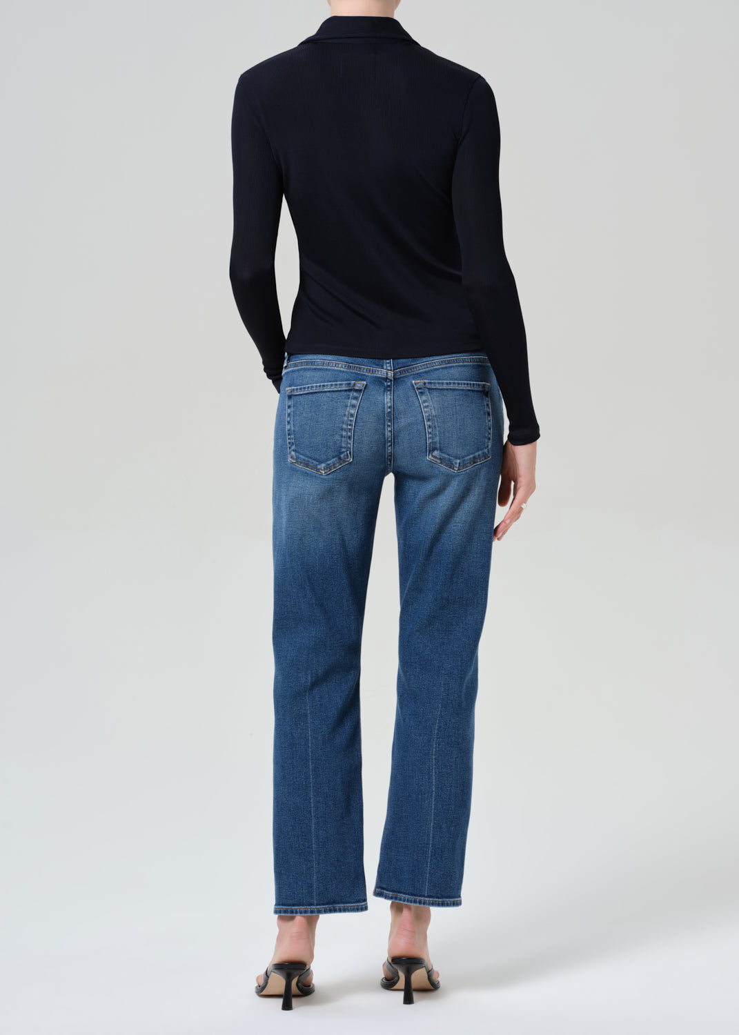 Person wearing a navy shirt and blue jeans on a grey background