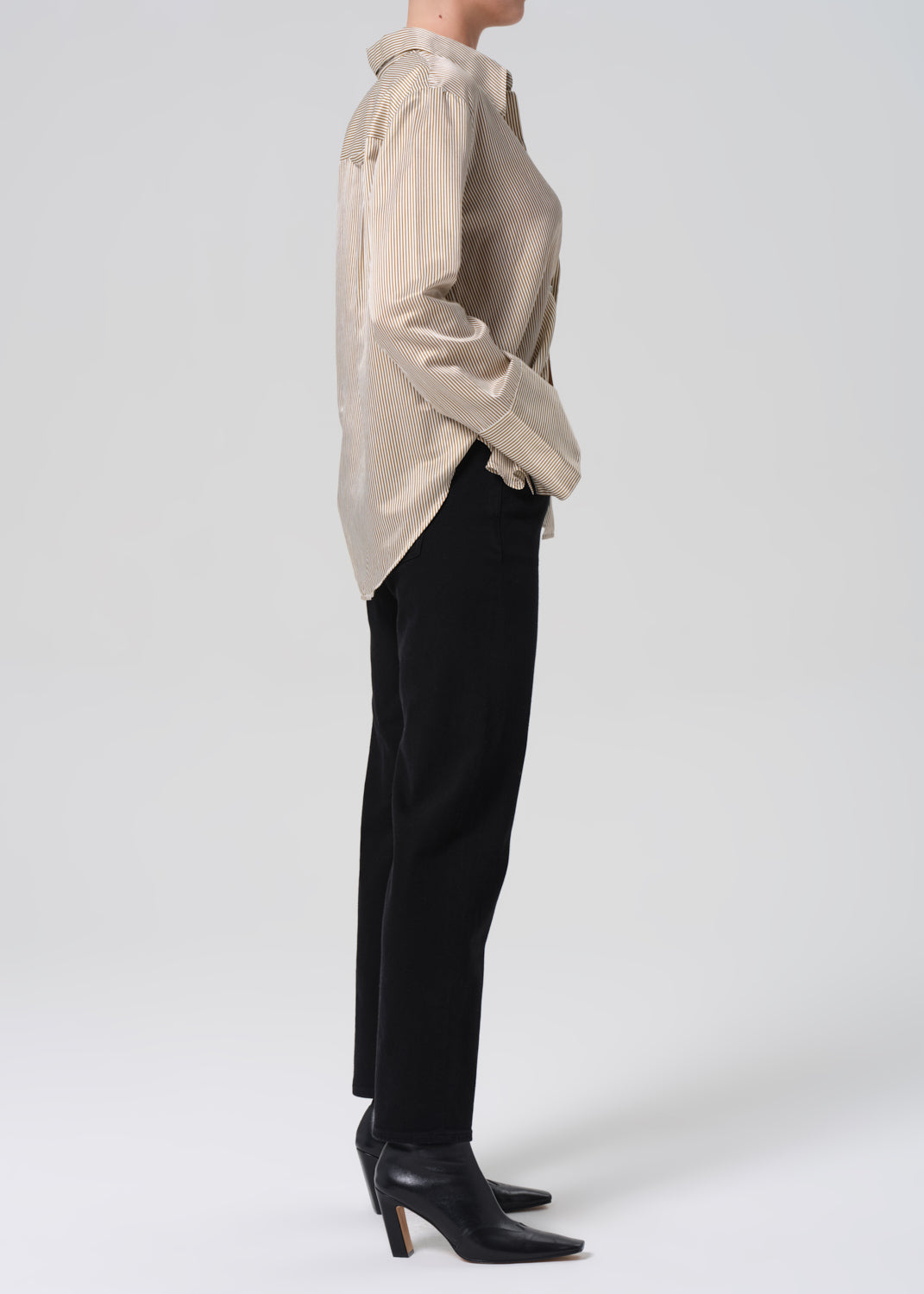 Person wearing a beige shirt, black pants, and black shoes on a white background