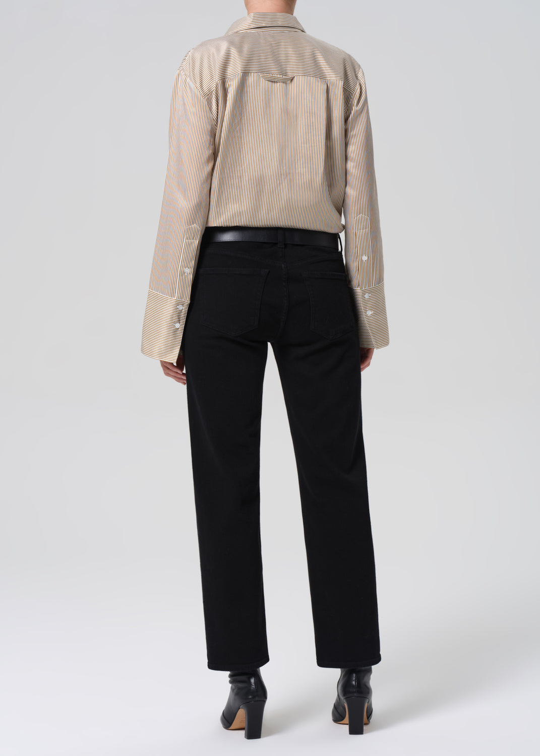 Person wearing a beige shirt and black pants on a white background