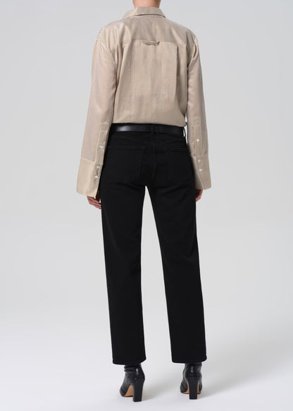 Person wearing a beige shirt and black pants on a white background