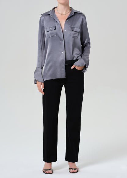 Person wearing a gray button-up shirt and black jeans on a grey background