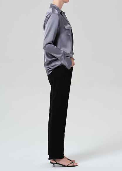 Person wearing a gray button-up shirt and black jeans on a grey background
