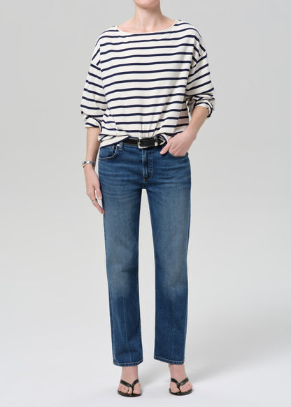 Person wearing a striped shirt and blue jeans on a grey background